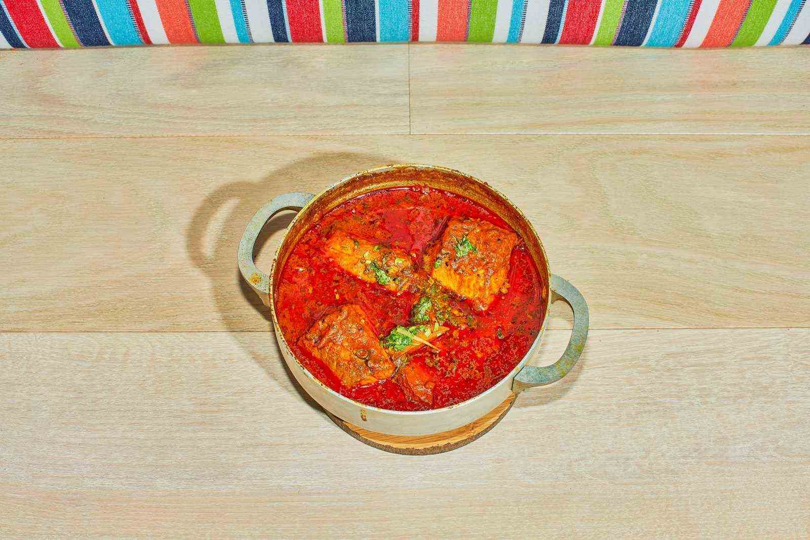 Ein bengalisches Fischcurry namens macher jhol wird in Dhamaka mit Babyhai-Kurkuma-Ingwer und Tomaten zubereitet.