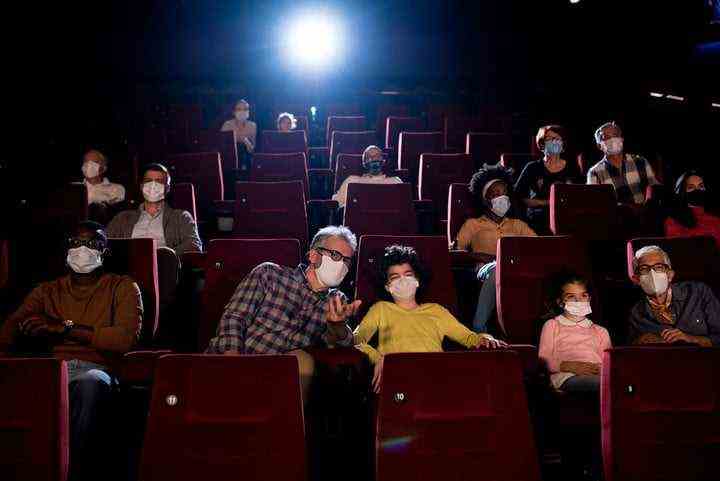 Kids and their grandparents wearing protective face masks while watching movies at the cinema.