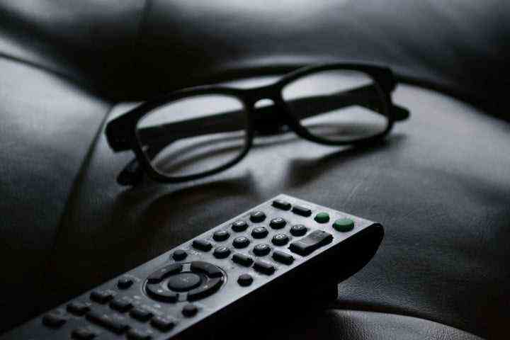 A black-and-white photo of a remote control and glasses.