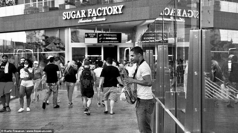 Musik machen: Ein besonders bewegendes Foto zeigt einen Mann, der vor dem Restaurant Sugar Factory Saxophon spielt, während die Menge an ihm vorbeigeht