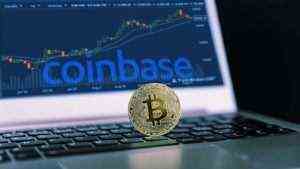 Ein Bitcoin ruht auf einem Computer mit dem Coinbase (COIN)-Logo und einem Trading-Chart.