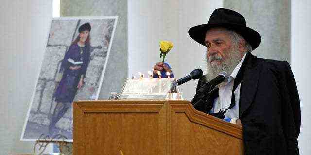 In diesem Aktenfoto vom 29. April 2019 hält Yisroel Goldstein, Rabbi von Chabad of Poway, eine gelbe Rose, als er bei der Beerdigung für Lori Kaye, die links abgebildet ist, in Poway, Kalifornien, spricht. Kaye, die getötet wurde Am 27. April 2019, als ein bewaffneter Mann in der Synagoge von Chabad of Poway das Feuer eröffnete, hatte Goldstein am Tag vor der Schießerei die Blume als Teil eines Blumenstraußes geschenkt, der auch Goldstein verletzte.  (AP Foto/Gregory Bull, Datei)