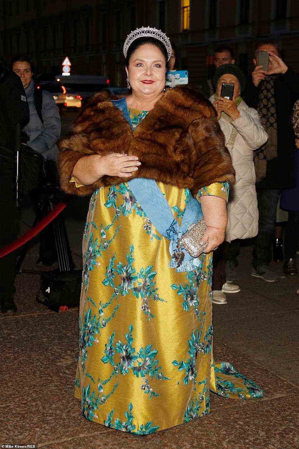 Quick change! After wearing a blue skirt and coat to the religious ceremony, the mother of the groom Duchess Maria Vladimirovna changed into a golden gown with rich floral embroidery and wrapped up in a fur stole for the evening festivities
