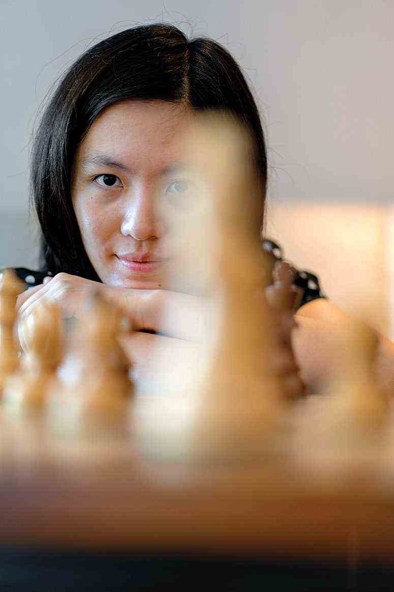 Hou Yifan blickt über beige Schachfiguren, im Vordergrund verschwommen 