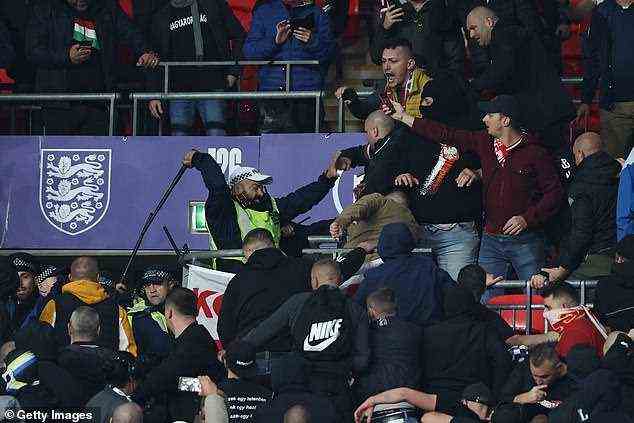 Ein Offizier benutzt seinen Schlagstock, um ungarische Fans, die versuchen, im Stadion zu kämpfen, wegzustoßen
