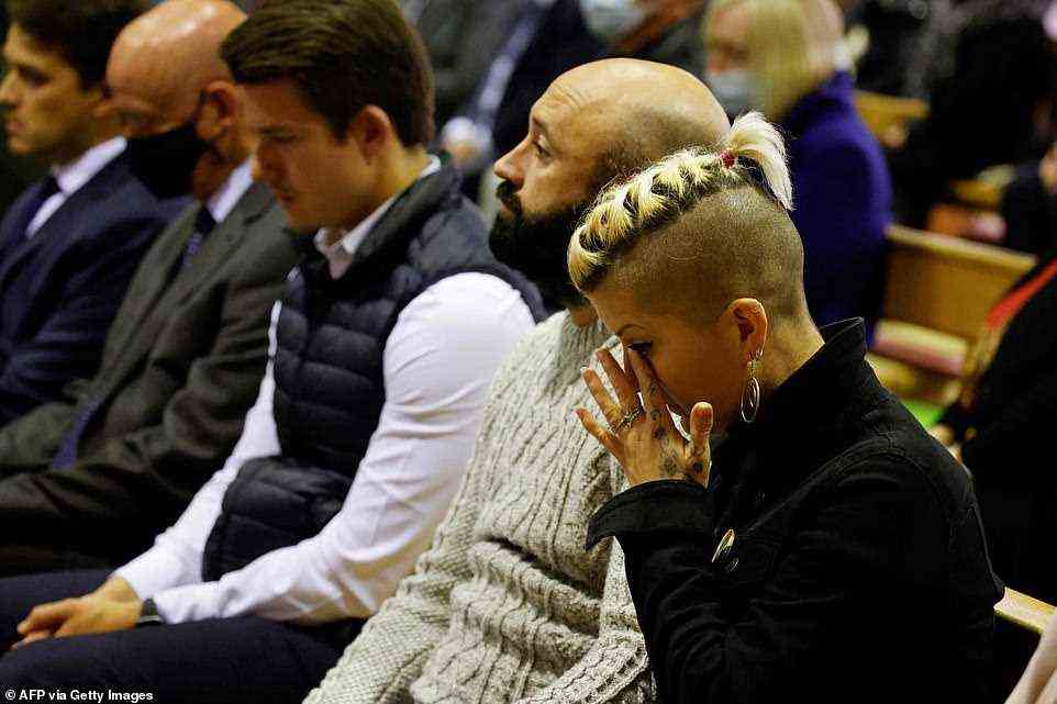 A woman wipes her tears as people attend a mass in memory of Conservative British lawmaker David Amess this evening