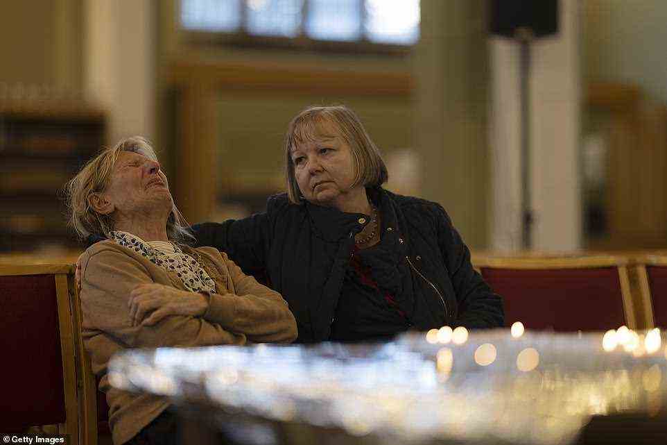 Constituent Ruth Verrinder (R) and former mayor Judith McMahon (L) gather their thoughts before lighting a candle
