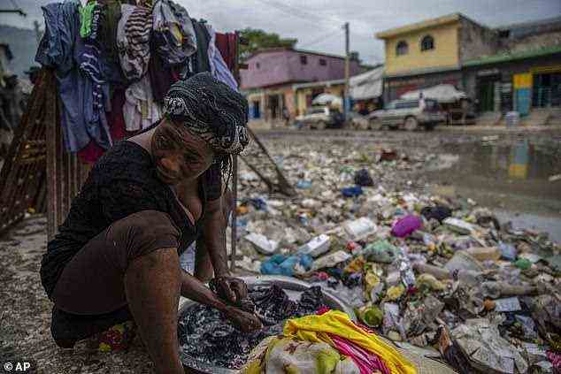 Ronise Lindor does the laundry next to a street flooded with garbage in the Portail neighborhood of Port-au-Prince, Haiti, seen earlier this month