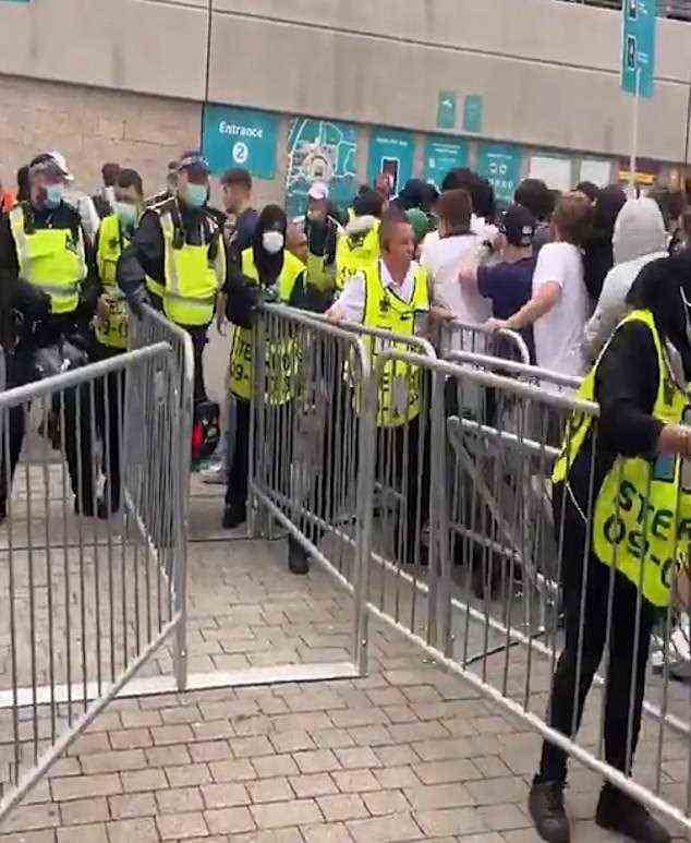 Eine Gruppe von Fußballfans stürmt durch die Sicherheitsbarrieren in Wembley, während Ordner verzweifelt versuchen, sie vor dem Finale der Euro 2020 in Wembley zurückzuhalten