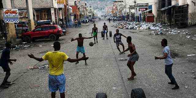 Jugendliche spielen am Montag in Port-au-Prince, Haiti, neben Geschäften, die wegen eines Generalstreiks geschlossen sind, Fußball.