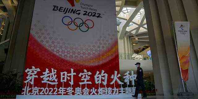 Ein Wachmann, der eine Gesichtsmaske trägt, um die Ausbreitung des Coronavirus einzudämmen, patrouilliert an einer Dekoration der Olympischen Winterspiele 2022 in Peking vorbei, um eine Begrüßungszeremonie für den Rahmen der Olympischen Winterspiele Peking 2022 im Olympiaturm in Peking am Mittwoch abzuhalten.