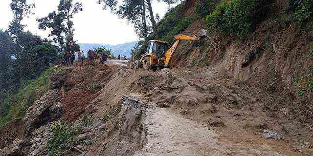Ein Bagger hilft bei der Räumung einer von Erdrutschen betroffenen Straße nach heftigen Regenfällen in Dipayal Silgadhi, Nepal, am Donnerstag.