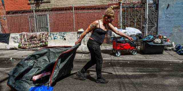 Eine obdachlose Frau, die nach der Straßenreinigung ihre Habseligkeiten schleppte, kam im Mai 2020 durch, um die Willow Street in San Francisco zu reinigen.