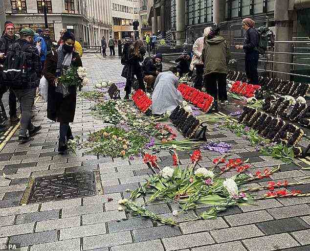 Blumen werden vor Lloyd's of London zurückgelassen, da Demonstranten das Unternehmen drängen, die Finanzierung der Nutzung fossiler Brennstoffe einzustellen