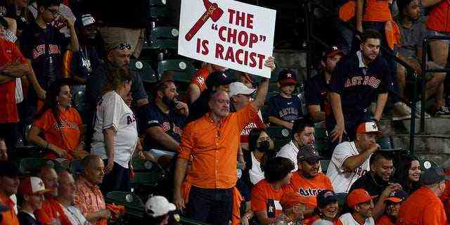 Ein Fan hält ein Schild mit der Aufschrift "das hacken ist rassistisch" während des neunten Innings im ersten Spiel der World Series während des neunten Innings im Minute Maid Park am 26. Oktober 2021 in Houston, Texas.