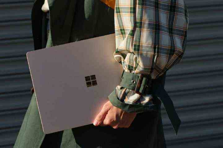 Eine Person, die einen Surface-Laptop trägt.