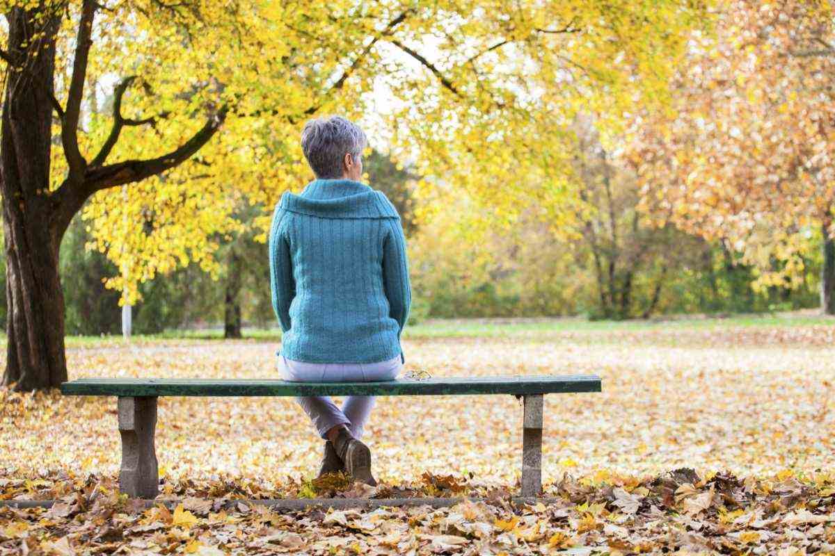 Reife Frau auf Bank im Herbstpark.