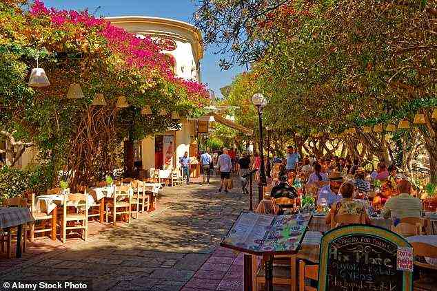 Café-Kultur: In Griechenlands hübscher Stadt Kos genießen die Menschen ein Essen im Freien unter Bäumen