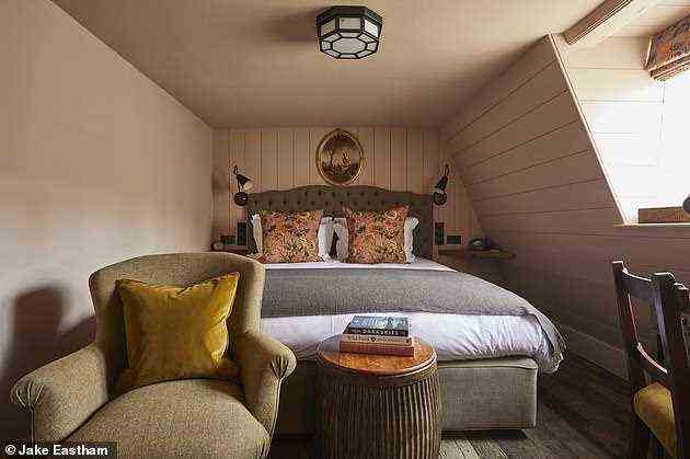 Dieses Schlafzimmer hat eine Holzvertäfelung an den Wänden und einen Sessel zum Kuscheln mit einem Buch