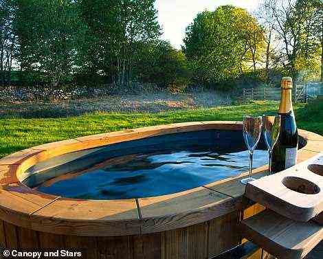 The hut is by a stream in the corner of a sheep field, and it comes with its own hot tub (pictured)