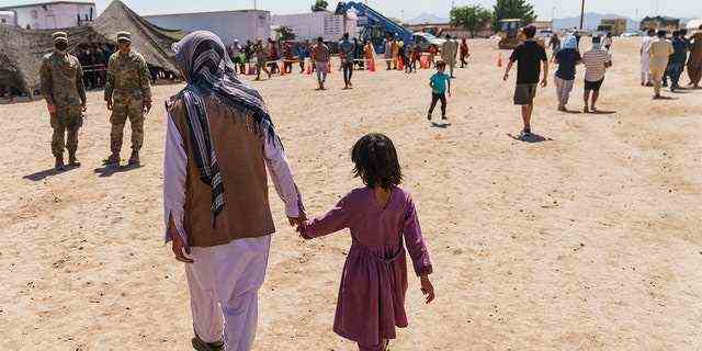 Ein Mann geht mit einem Kind durch das Dorf Doña Ana von Fort Bliss, in dem afghanische Flüchtlinge in New Mexico untergebracht sind.  Das Heimatschutzministerium bestreitet nicht, dass Hunderte Afghanen, die auf US-Militärstützpunkten untergebracht sind, die Einrichtungen verlassen haben. 