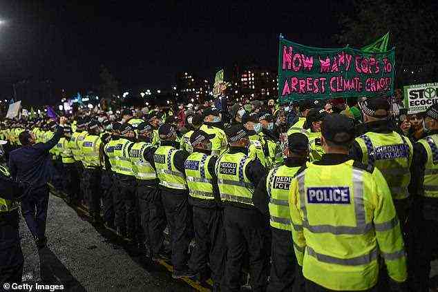 Im Bild: Polizisten eskortieren einen Protest der Extinction Rebellion außerhalb des COP26-Gipfels, als ein Banner mit der Aufschrift 