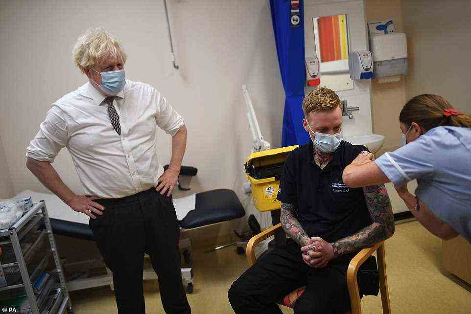 Prime Minister Boris Johnson watches as nurse Sandra Guy gives a Covid-19 booster jab to an NHS facilities worker during a visit to Hexham General Hospital in Northumberland yesterday