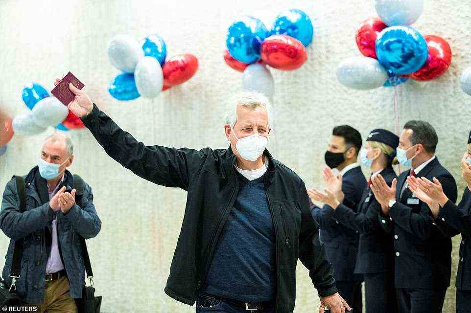 A man carrying a British passport arrives to applause at JFK on Monday morning on one of the first tourist flights from the UK