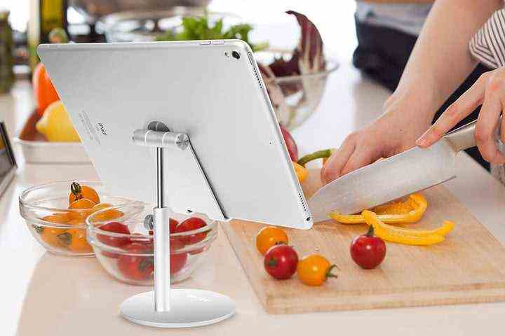A person using the AICase Telescopic Adjustable iPad Stand Holder while chopping vegetables in a kitchen.
