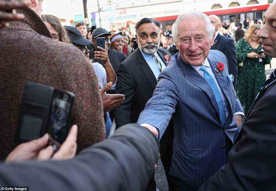 Prince Charles shakes hands with a well-wisher outside a NatWest bank branch in Brixton, South London, this morning