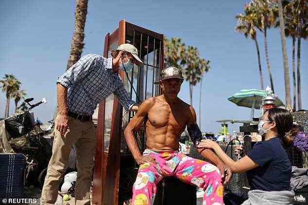 Venice Family Clinic's Director of Homeless Services Dr. Coley King, left, treats Kenard Durr, center, at the world-famous beach. A homeless encampment at the beach has exploded during COVID lockdown (April 20)