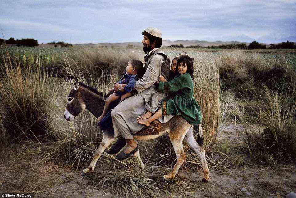 Eine Familie reitet auf einem Esel in Maimana, Afghanistan, auf einem Bild aus dem Jahr 2003. McCurry erklärt, dass hier der Vater seine Kinder von einem Ausflug zum Markt nach Hause bringt