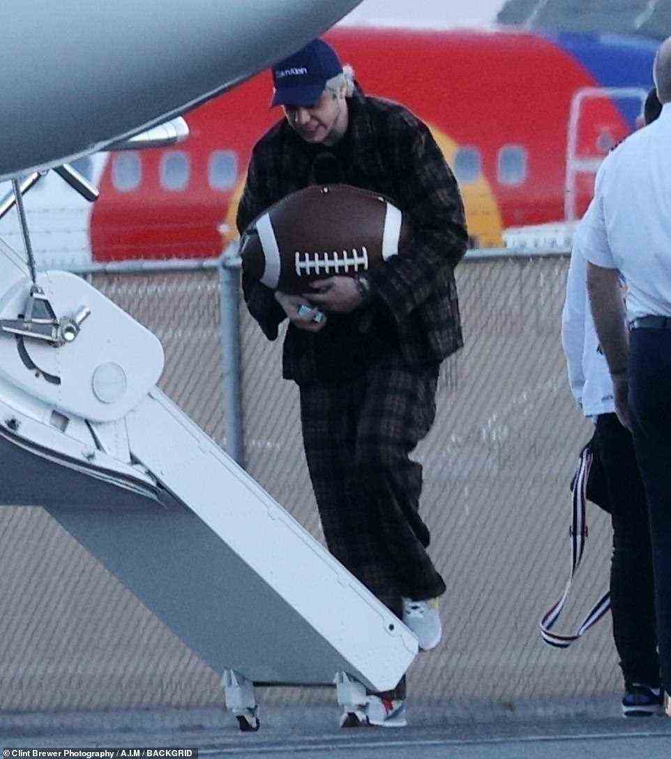 Supplies: The King Of Staten Island star had what looked like a pack of cigarettes in his hand as he carried a huge football-shaped bag on board