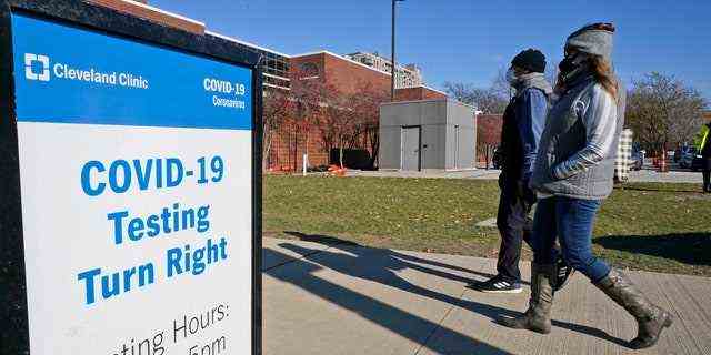 Zwei Personen gehen am Mittwoch, 18. November 2020, in Cleveland, Ohio, an einem Schild für COVID-19-Tests in der Cleveland Clinic vorbei.  (AP-Foto/Tony Dejak)