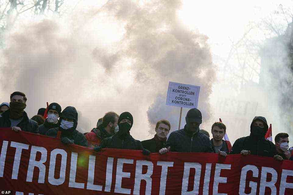 Protestors with a banner which reads 'Control the borders' attend a demonstration against measures to battle Covid in Vienna
