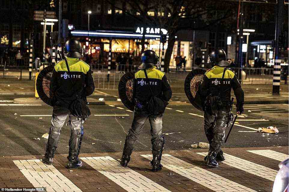 Dutch Police (pictured last night) tweeted that rioters started fires and threw fireworks during the rioting and authorities closed the city's main railway station as officers lined up on the streets of Rotterdam amid chaotic scenes in the Netherlands