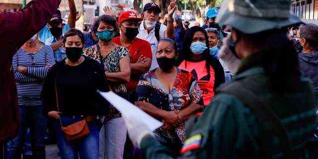 Menschen streiten mit Wahlbeamten in einem Wahllokal, das während der Regionalwahlen im Stadtteil San Agustin in Caracas, Venezuela, am Sonntag, den 21. November 2021, nicht rechtzeitig geöffnet wurde. Venezolaner gehen zu den Urnen, um Gouverneure der Bundesstaaten und andere lokale Beamte.  (AP Foto/Jesus Vargas)