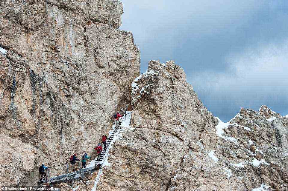 Abgebildet sind Wanderer, die den Monte Cristallo besteigen, der auf der Via Ferrata Ivano Dibona . zu sehen ist