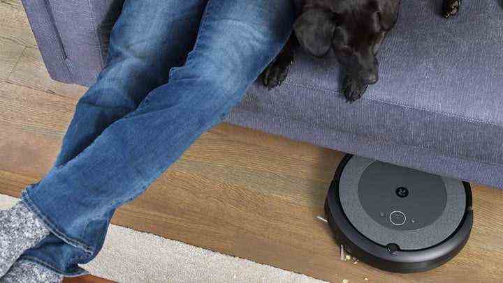 A puppy on a couch watching an iRobot Roomba i3 (3150) Robot Vacuum.