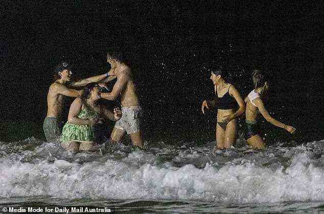 A group of friends are seen enjoying a swim in the ocean and joke around in the surf in Byron Bay on Saturday night