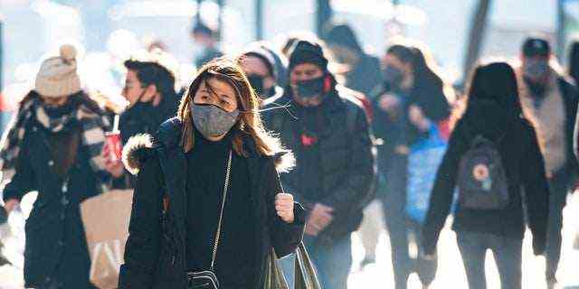 Die Menschen tragen Einkaufstaschen auf der Fifth Avenue, während die Stadt die Wiedereröffnungsbemühungen nach den am 21. Dezember 2020 in New York City verhängten Beschränkungen zur Verlangsamung der Ausbreitung des Coronavirus fortsetzt.  (Foto von Noam Galai/Getty Images)