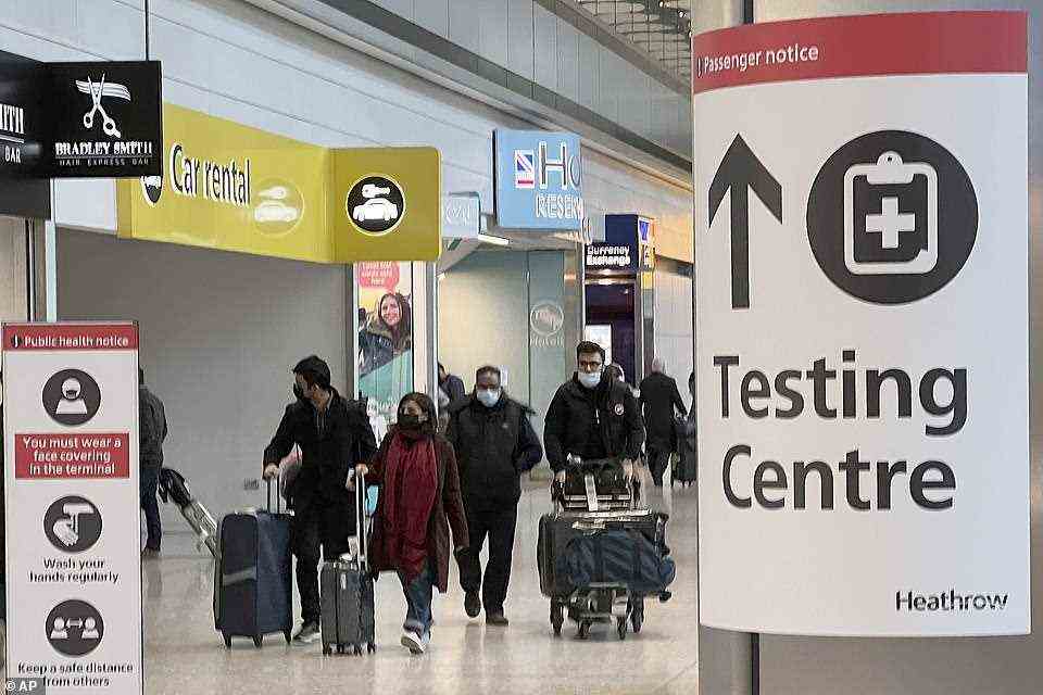 Passengers arrive at Heathrow Airport this morning as a testing centre sign is seen
