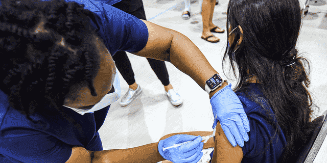 Eine Krankenschwester verabreicht einem Mädchen in einer COVID-19-Impfstoffklinik der Lyman High School in Longwood am Tag vor Beginn des Unterrichts für das Schuljahr 2021-22 eine Dosis des Pfizer-Impfstoffs. 