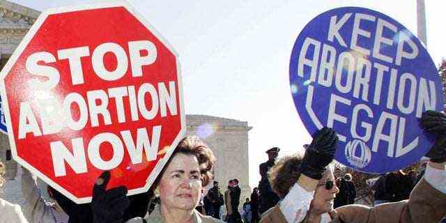 FILE - In this Nov. 30, 2005 file photo, an anti-abortion supporter stands next to a pro-choice demonstrator outside the U.S. Supreme Court in Washington. The new poll from The Associated Press-NORC Center for Public Affairs Research finds 61% of Americans say abortion should be legal in most or all circumstances in the first trimester of a pregnancy. However, 65% said abortion should usually be illegal in the second trimester, and 80% said that about the third trimester. (AP Photo/Manuel Balce Ceneta)