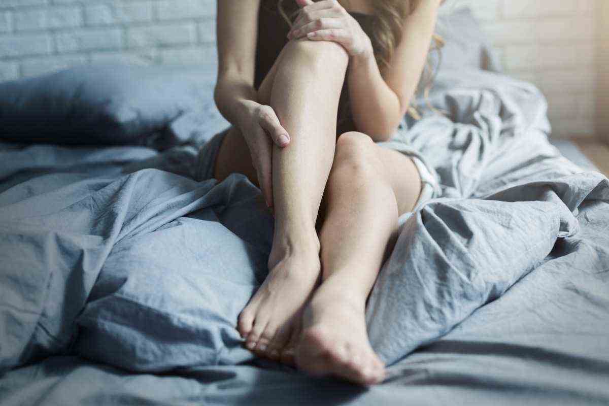 Weibliche Beine im Bett, Nahaufnahme.  Körper- und Hautpflege für Frauen, müde Beine nach dem Arbeitstag oder Fitnesstraining