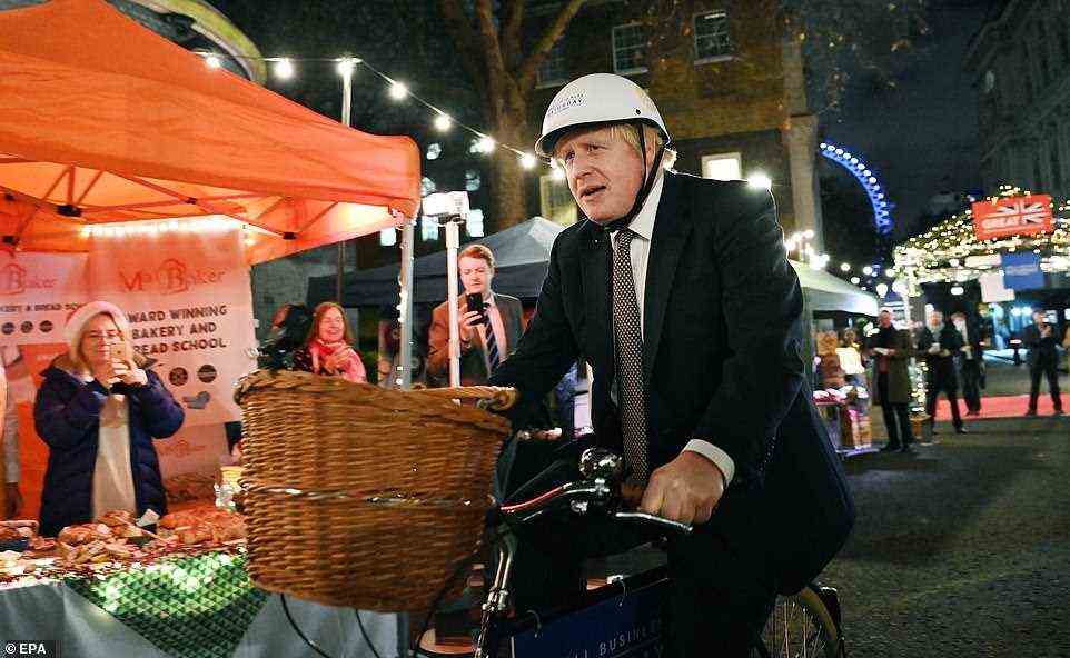 Boris Johnson rides on a bicycle around a Christmas market outside 10 Downing Street in London on Tuesday evening