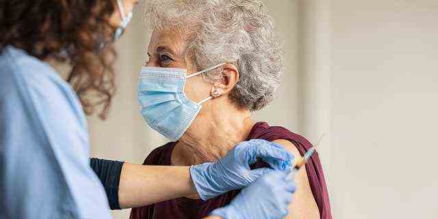 Allgemeinmediziner, der alten Patienten in einer Privatklinik mit Kopienraum impft.  Arzt, der einer älteren Frau im Krankenhaus eine Injektion gibt.  Krankenschwester, die eine Spritze hält und Baumwolle verwendet, bevor sie einen Covid-19- oder Coronavirus-Impfstoff herstellt.