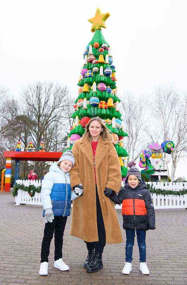 Kimberly Walsh und die Söhne Bobby und Cole lächelten an ihrem festlichen Familientag vor dem riesigen 364.000 DUPLO-Weihnachtsbaum aus Ziegelsteinen