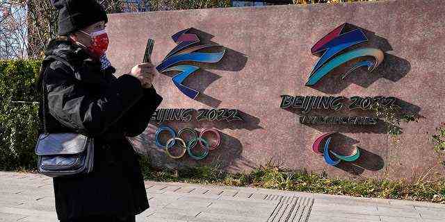Ein Besucher des Shougang Parks geht am Dienstag, 9. November 2021, in Peking, China, an den Logos der Olympischen Winterspiele und Paralympics in Peking vorbei. 