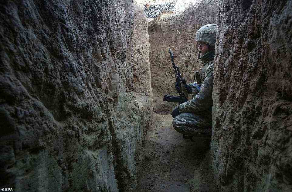 A Ukrainian soldier crouches in a trench near the frontline with Russia, where a proxy-war has been fought against Russian-backed separatists for years